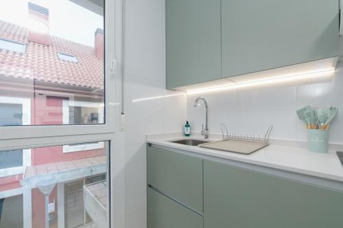 une cuisine blanche avec un évier et une fenêtre dans l'établissement Playa y descanso con parking by CABANA Rentals, à Ribeira