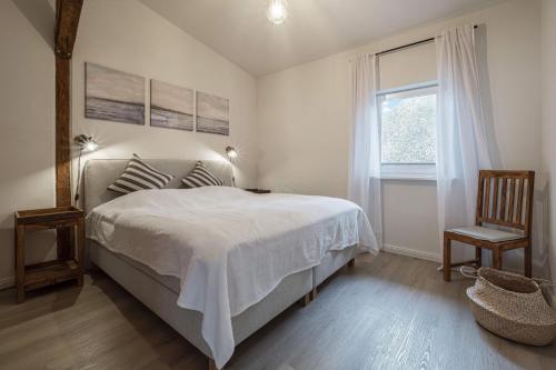 a bedroom with a bed and a chair and a window at Ostscheune am Mühlendamm in Steinbergkirche