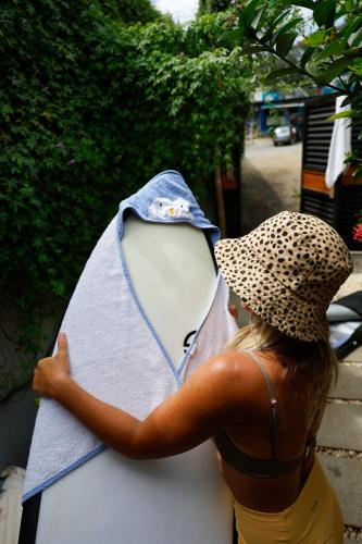 a woman wearing a hat holding a surfboard at The Cafecito Surfhouse - Santa Teresa in Santa Teresa Beach