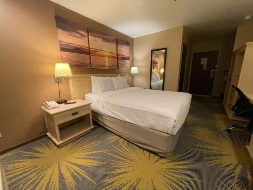 a hotel room with a bed and a night stand at Days Inn by Wyndham Seatac Airport in SeaTac