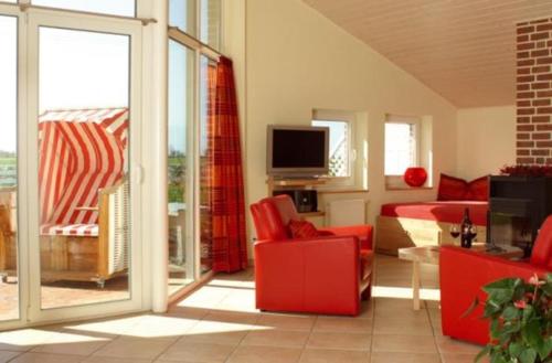 sala de estar con sillas rojas y TV en Haus an der Pferdekoppel C eingezäunt 130m, en Fehmarn