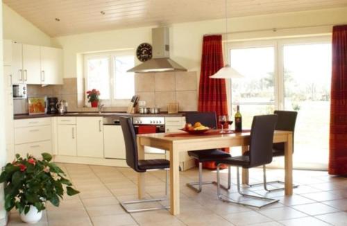Una cocina con una mesa de madera y sillas negras. en Haus an der Pferdekoppel C eingezäunt 130m, en Fehmarn