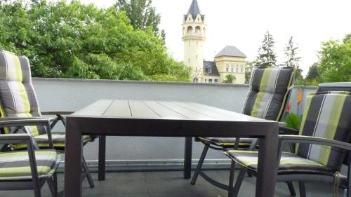 a table and chairs on a balcony with a clock tower at Apartment Kunsthaus Panorama 1 OG mit Balkon in Nordhausen