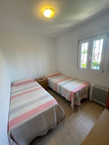 twee bedden in een kamer met witte muren en ramen bij Tu casa en Doñana in Matalascañas