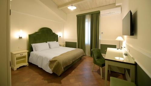 a hotel room with a bed and a desk and a television at Tenuta Ciminata Greco in Rossano