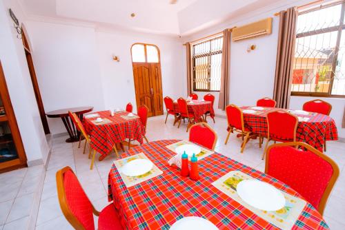 a dining room with red chairs and tables and tablesktop at WILIVINA HOTEL in Dar es Salaam
