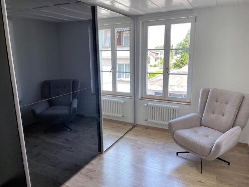 a living room with a chair and a mirror at Grosse Neue Wohnung in Bern mit Whirlpool in Bern
