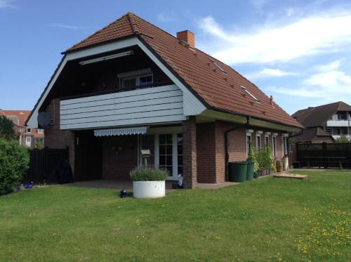 a house with a porch and a grass yard at Fewo Hoogen in Strandnähe in Friedrichskoog-Spitz