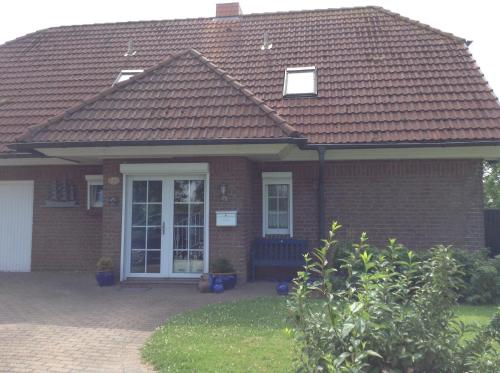 a brick house with a bench in the front yard at Fewo Hoogen in Strandnähe in Friedrichskoog-Spitz