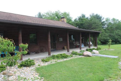 Cabaña de madera con porche y patio en Bushwood Cabin, en Logan