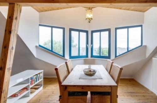 a dining room with a table and chairs and windows at 3-Raum Dachgeschoss Apartment 54 in Rankwitz