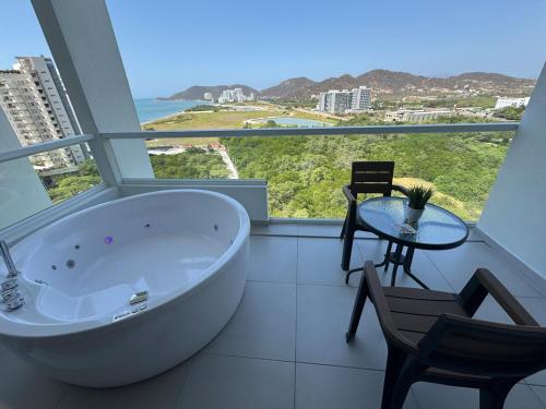 a bathroom with a tub and a table and chairs at Suite con Lujoso Jacuzzi, Piso 14 y vista al mar in Santa Marta