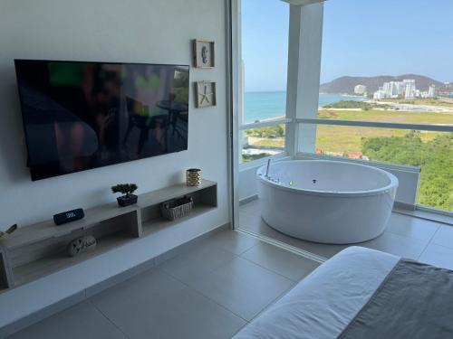 a white bathroom with a large tub and a tv at Suite con Lujoso Jacuzzi, Piso 14 y vista al mar in Santa Marta