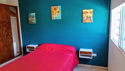 1 dormitorio con cama roja y pared azul en El Buen Vivir, en Mar del Plata