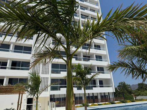 an apartment building with palm trees in front of it at Suite con Lujoso Jacuzzi, Piso 14 y vista al mar in Santa Marta