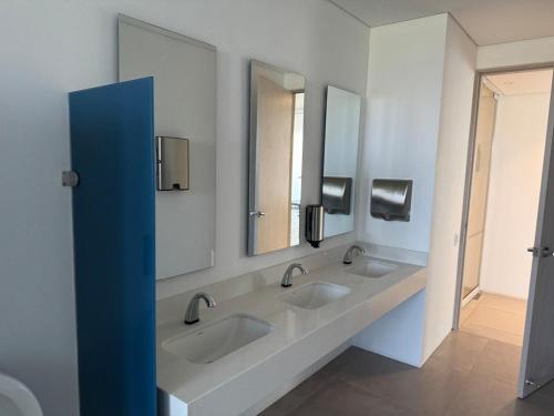 a bathroom with three sinks and two mirrors at Suite con Lujoso Jacuzzi, Piso 14 y vista al mar in Santa Marta