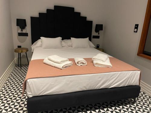 a bedroom with a large bed with towels on it at Apartamentos Maguilla IV- Parking incluido para huéspedes in Badajoz
