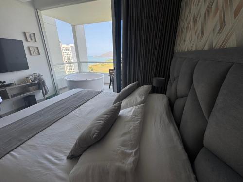 a bedroom with a bed with a view of the ocean at Suite con Lujoso Jacuzzi, Piso 14 y vista al mar in Santa Marta