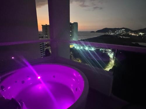 a purple bath tub in a room with a window at Suite con Lujoso Jacuzzi, Piso 14 y vista al mar in Santa Marta