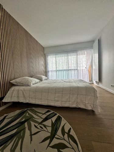 une chambre avec un grand lit et une fenêtre dans l'établissement appartement spacieux, à Clichy