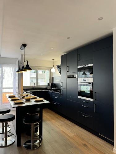 une cuisine avec des placards noirs et une table avec des tabourets dans l'établissement appartement spacieux, à Clichy