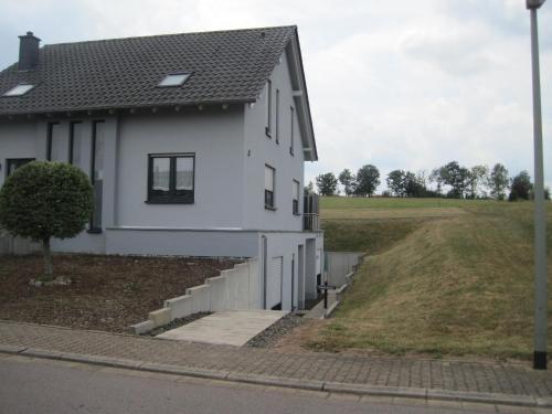 a white house with stairs and a field at Ferienwohnung-Haus-Perkow in Illingen