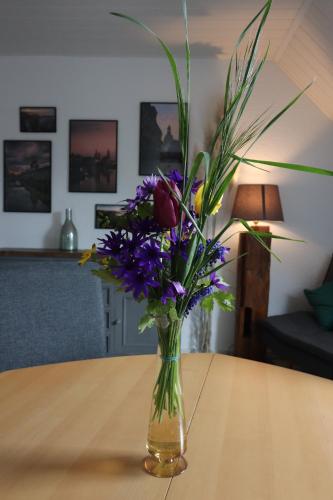 a vase filled with purple flowers on a table at Ferienwohnung am Barockgarten in Heidenau