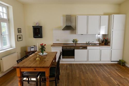 NeuenkirchenFerienwohnung 2 mit schönem Seeblick的配有白色橱柜和木桌的厨房
