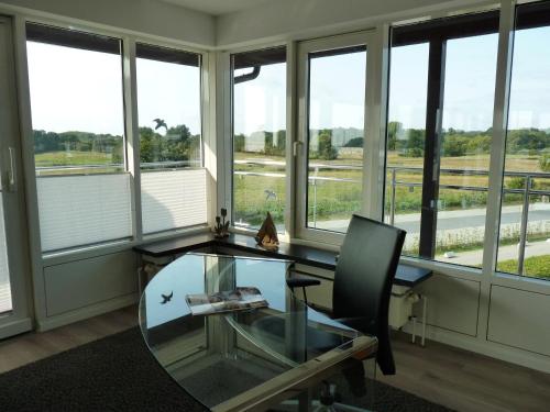 an office with a glass desk and a chair and windows at ancora Marina Haus 2 Penthouse in Neustadt in Holstein