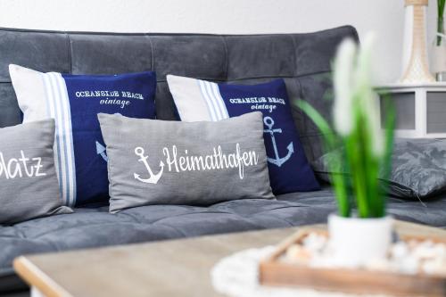 a couch with pillows on it with a table at Ferienwohnungen Haus Boje "Scholle" in Neuharlingersiel
