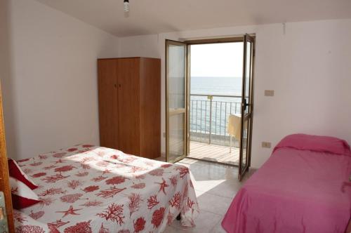 a bedroom with a bed and a balcony with the ocean at Paradiso in riva al mare in Belmonte Calabro