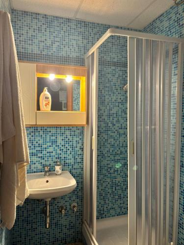 a blue tiled bathroom with a sink and a shower at B&B AFFITTACAMERE Mo' MONTEIASI in Monteiasi