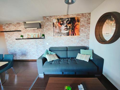 a living room with a blue couch and a brick wall at Cocoon'Inn Blagnac in Blagnac