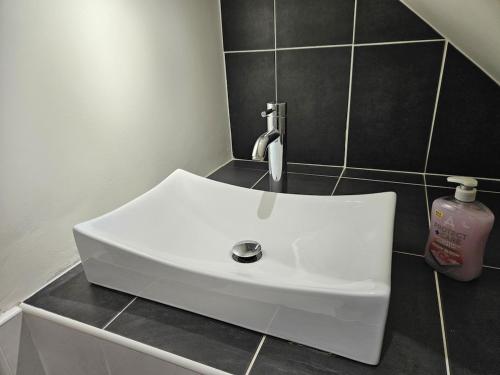 a white sink in a bathroom with black tiles at Forthill Lodge in Enniskillen