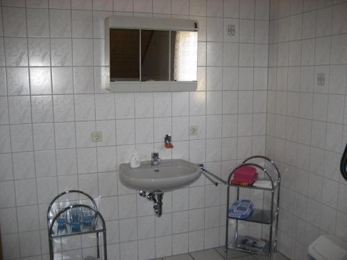 a white tiled bathroom with a sink and a mirror at Marianne in Ludwigswinkel