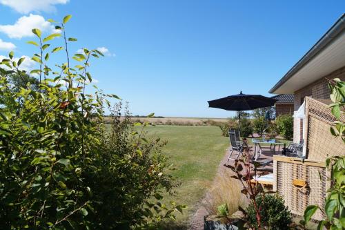 un patio avec un parasol, une table et des chaises dans l'établissement Ferienhaus Ankerplatz FH2, à Fehmarn