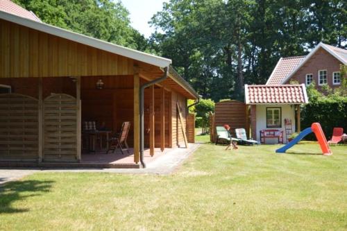 a backyard with a house and a playground at Ferienhaus beim Rosengarten in Holthaus