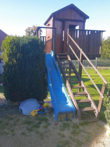 a playground with a slide and a wooden house at FeWo oben in Kalletal