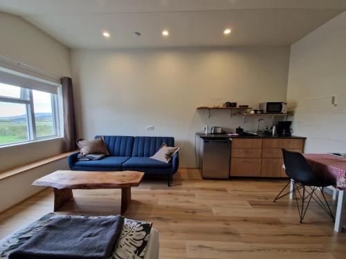 a living room with a blue couch and a table at Svansholl Apartments in Laugarholl