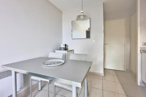 une salle à manger blanche avec une table et des chaises dans l'établissement Résidence La Pinède - maeva Home - Appartement 2 pièces 4 personnes vue Mer - Sélection MAE-4181, à Hyères