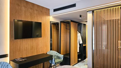 a hotel room with a tv on the wall and a dressing room at Hotel Bucura in Călimăneşti