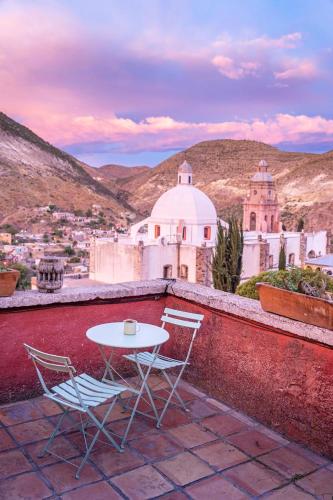 a table and chairs on a balcony with a view of a city at Casa Sulahue in Real de Catorce