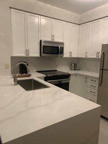 a kitchen with white cabinets and a sink and a microwave at Cityscape in Mississauga