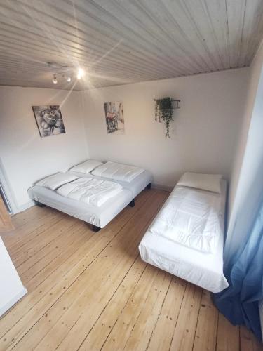 two beds in a room with a wooden floor at Calm and cozy apartment with free parking in Hjørring