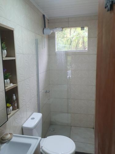 a white bathroom with a shower and a toilet at Canto do Beija-flor Rolante RS in Rolante