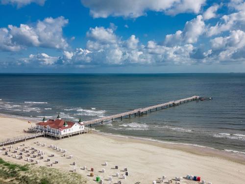 a beach with chairs and a pier and the ocean at Villa Carmen Sandburg in Ahlbeck