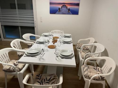 a white table and chairs with plates and glasses on it at Ruhig gelegene EG-Neubauwohnung mit Garten, Terrasse, Insektenschutz, Einbauküche für max 7 Personen in Südlohn