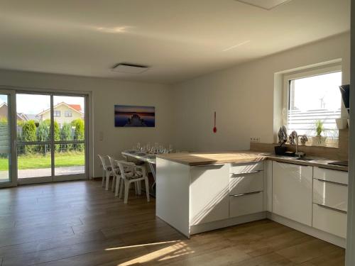 a kitchen with white cabinets and a table with chairs at Ruhig gelegene EG-Neubauwohnung mit Garten, Terrasse, Insektenschutz, Einbauküche für max 7 Personen in Südlohn