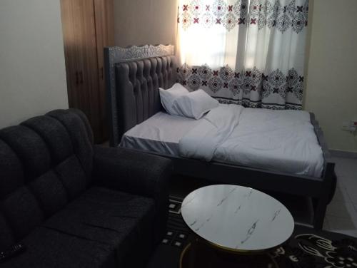 Un dormitorio pequeño con una cama y un sofá. en Joymu Plaza, en Kitengela 