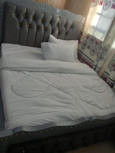 a large bed with white sheets and pillows at Joymu Plaza in Kitengela 